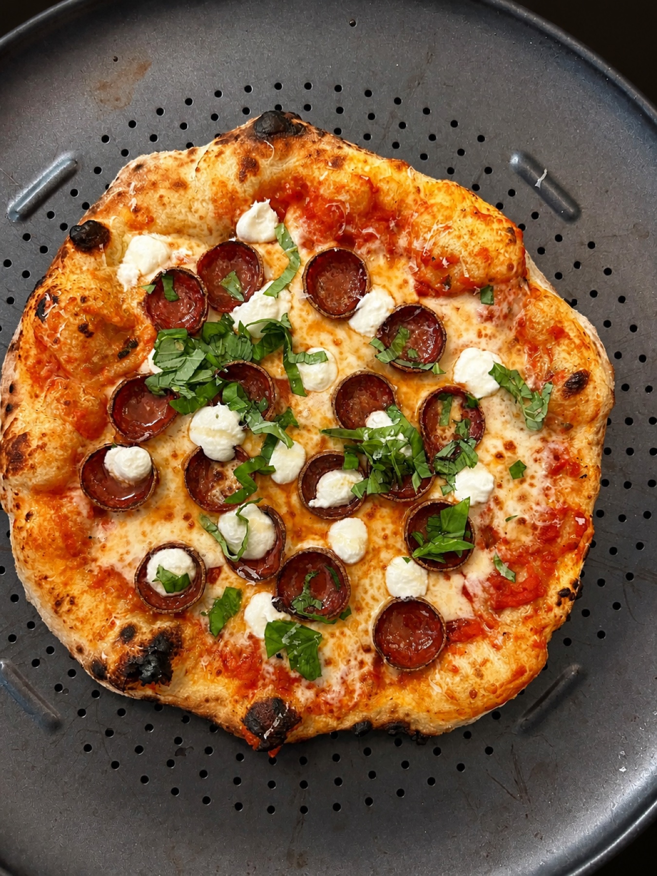A blistered pepperoni, ricotta, and basil pizza fresh from the oven