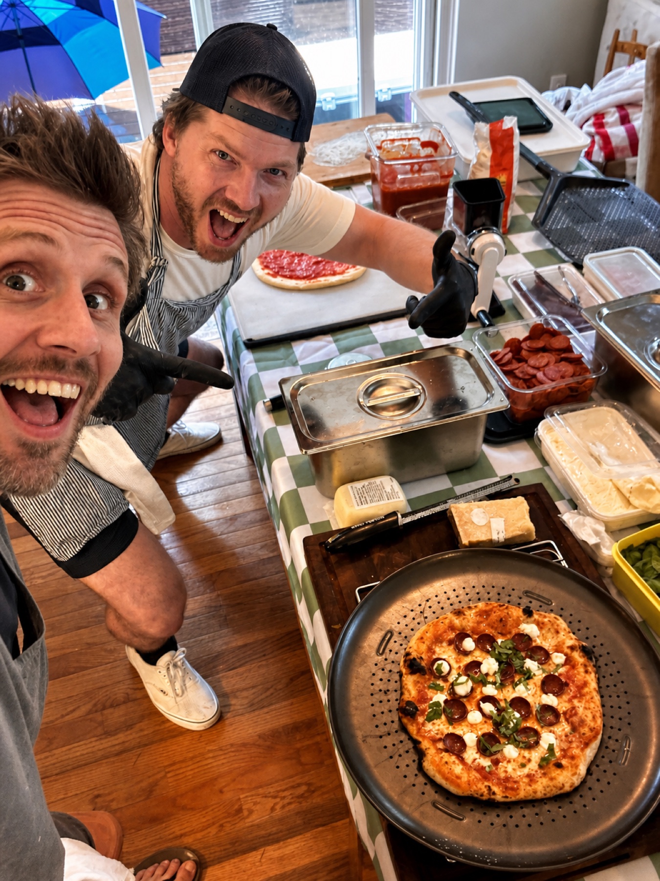 The two Pizza Night makers smiling beside a fresh pizza and their prep table