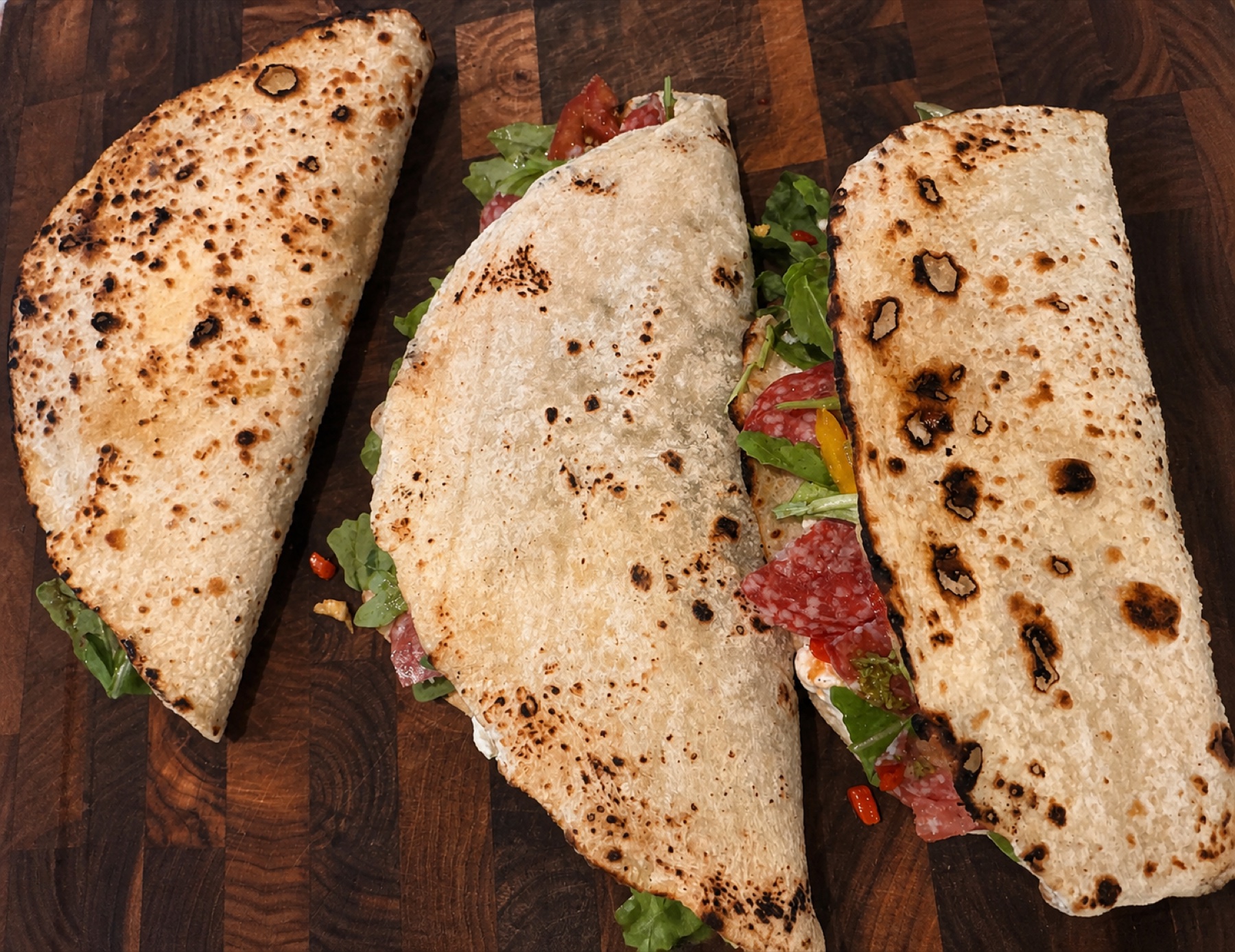 Three folded pizza sandwiches on a wooden board